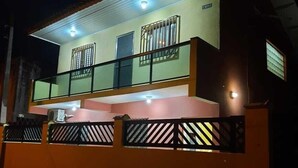 A two-story house with a balcony, a gated entrance, and a visible door.