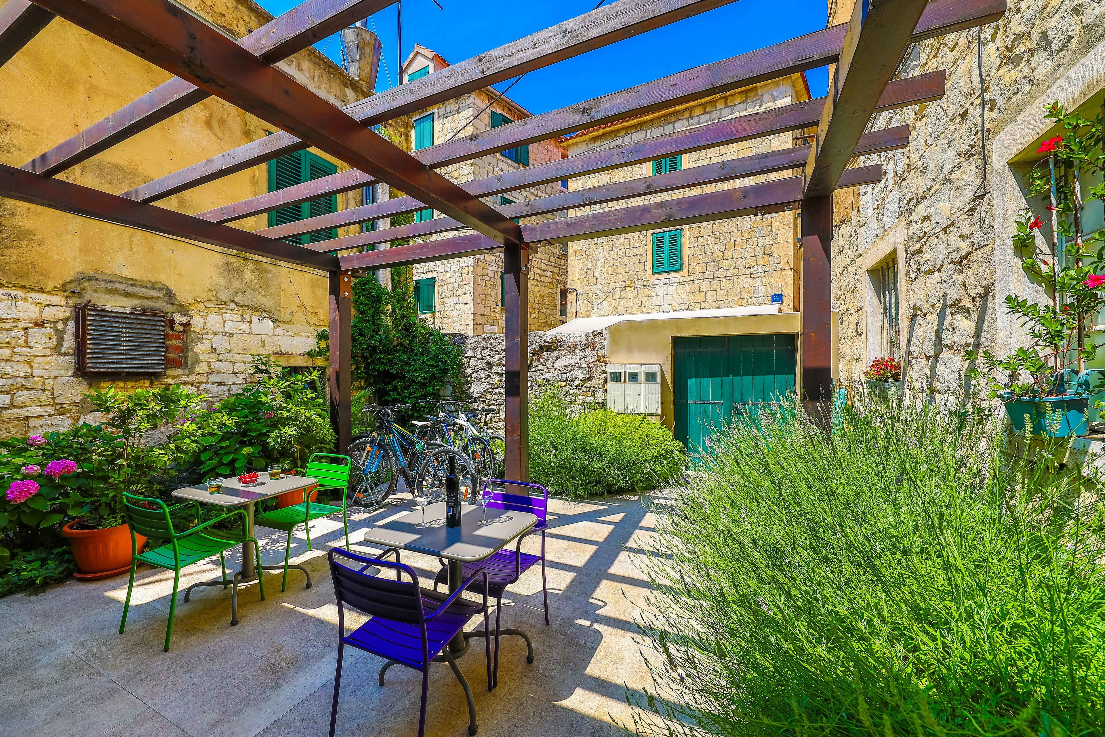 An outdoor patio with a table and chairs, surrounded by stone buildings and greenery.