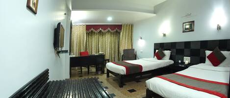 A hotel room with two beds, a desk, a chair, and a window with curtains.