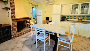 A compact kitchen with a dining table, chairs, a refrigerator, a microwave, and a tiled backsplash. - Badualga Pink (San Teodoro)