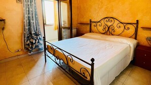 A bedroom with a bed, a radiator, a window with curtains, and a wall-mounted air conditioner. - Badualga Pink (San Teodoro)