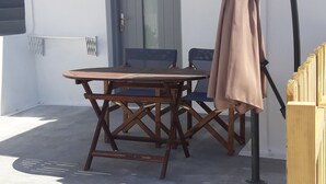 A patio with a wooden table and chairs, a door, and a lamp. - Maistrali Prive (Santorini)