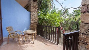 A balcony with wicker furniture, a stone wall, and a view of greenery. - Residence La Cinta 6 (San Teodoro)