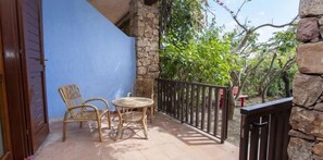 Enjoy a peaceful retreat on this balcony overlooking a serene garden with a wicker chair and table.