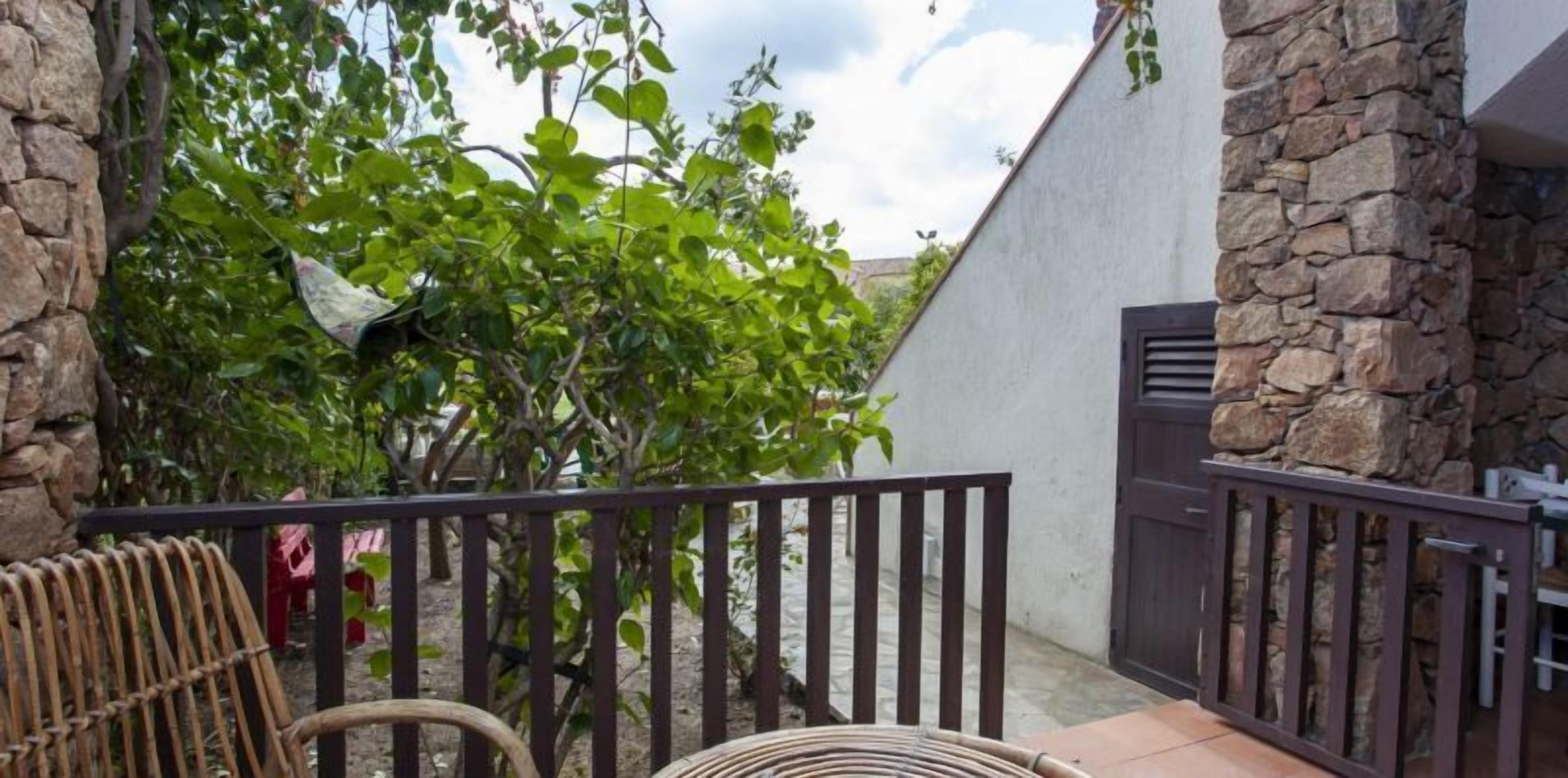 A stone wall, a wooden gate, and a wicker chair.