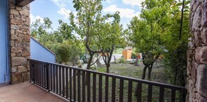 Overlooking a serene garden, this balcony offers a peaceful retreat with a stone wall and metal railing.