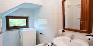 A bathroom with a window, a sink, and a mirror.