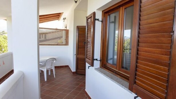 A narrow corridor with wooden shutters, a white chair, and a table. - Residence La Cinta 2 (San Teodoro)