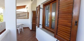 A narrow corridor with wooden shutters, a white chair, and a table.