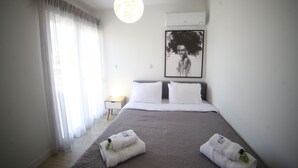 A modern hotel room with a large bed, white curtains, a hanging light fixture, and a framed artwork on the wall. - Athens Morum City Apartments (Vyronas)