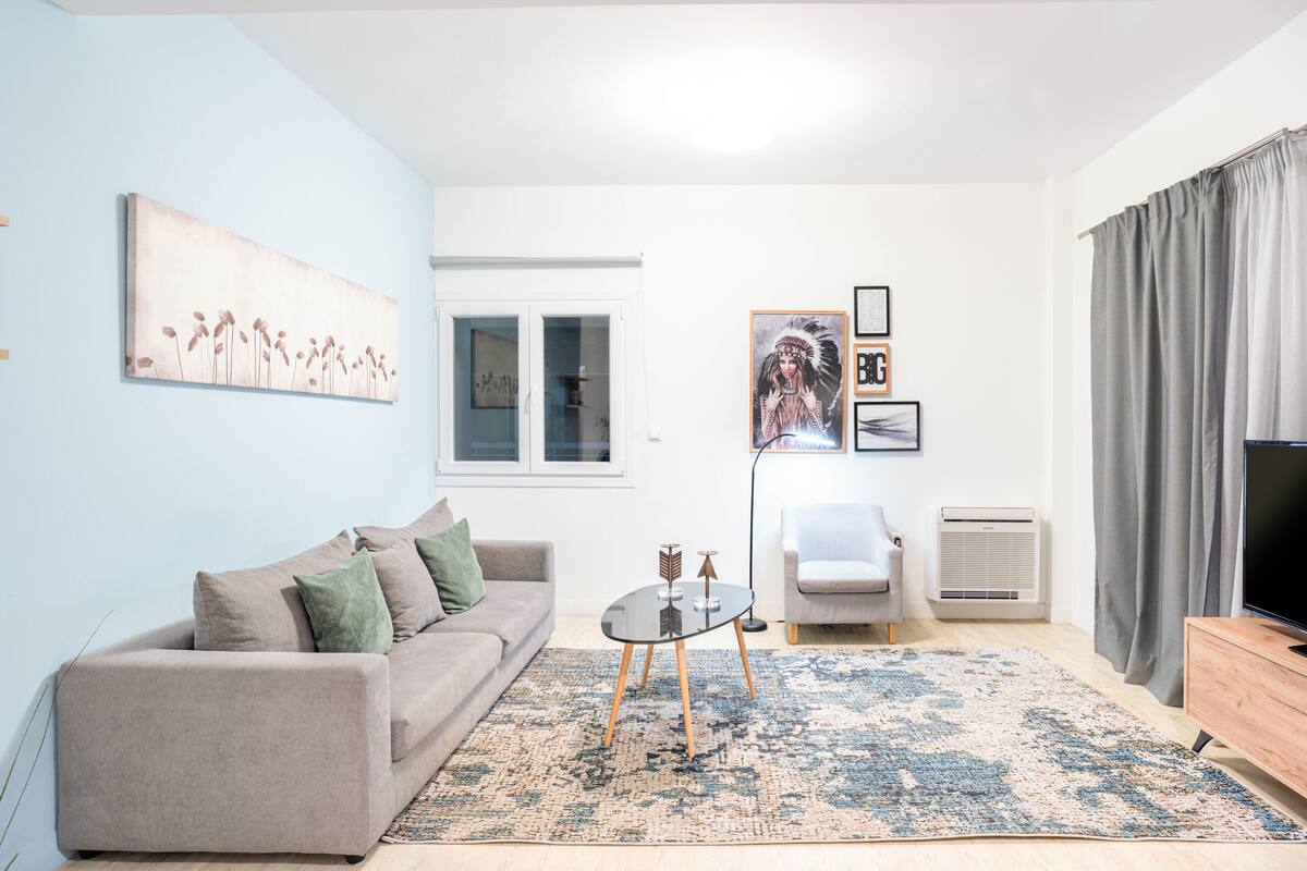 A modern living room with a sofa, a coffee table, a TV, and artwork on the walls.
