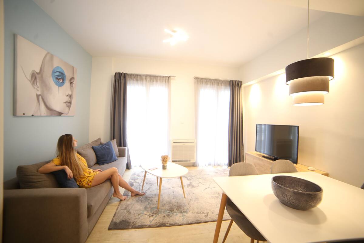 A living room with a sofa, a coffee table, a TV, and a dining table.