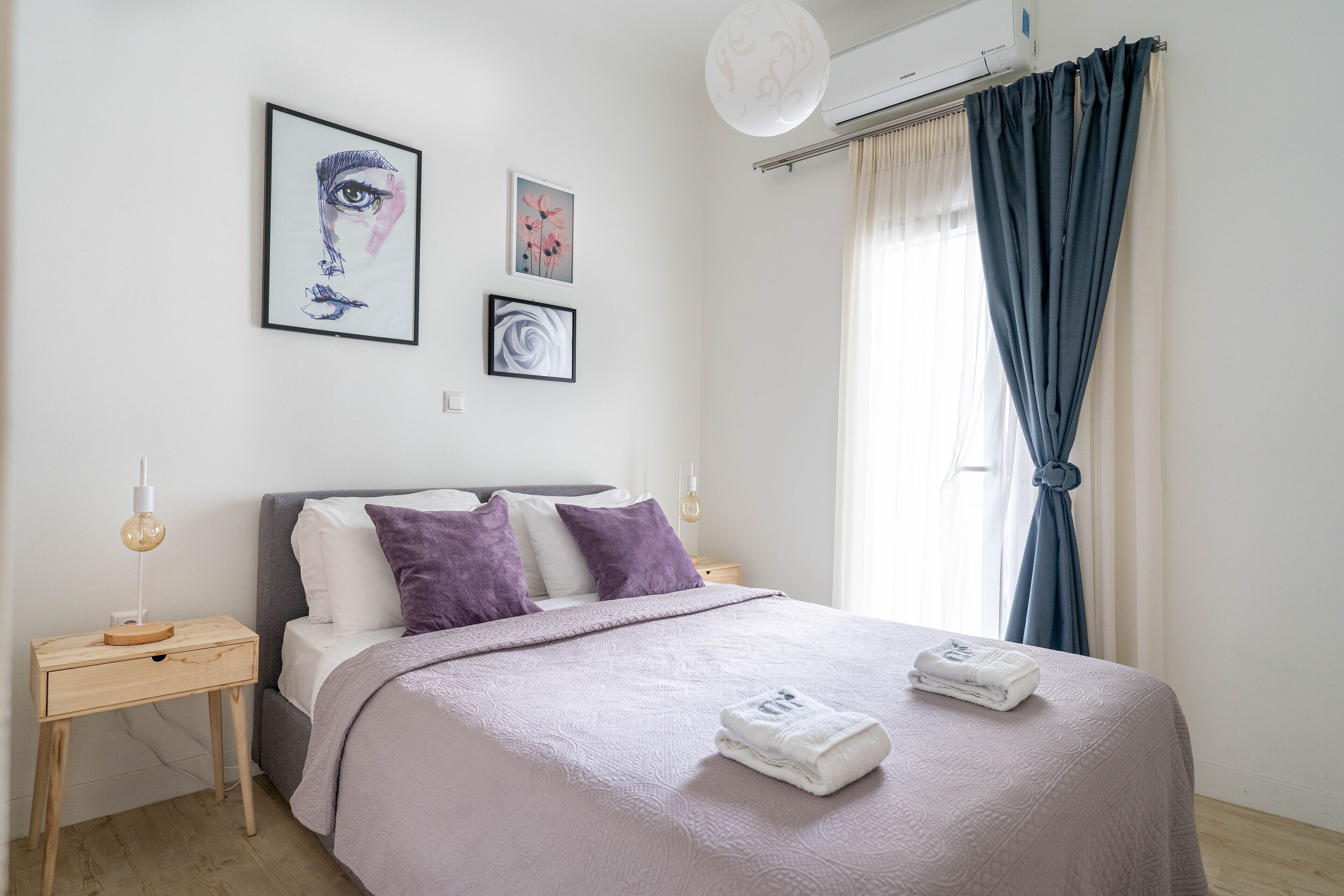 A neatly arranged bedroom with a bed, a bedside table, and a wall-mounted air conditioner.