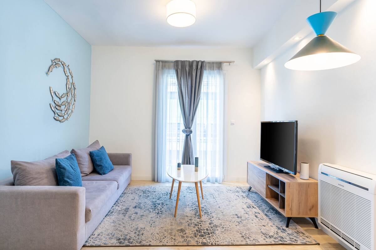 A modern living room with a sofa, a TV, a table, and a radiator.