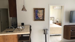 A modern kitchen with a wooden island, a hanging pendant light, and a framed painting on the wall.