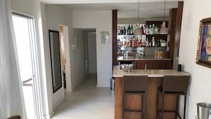 A modern kitchen with a bar area, featuring a countertop, bar stools, and a variety of bottles and glasses.
