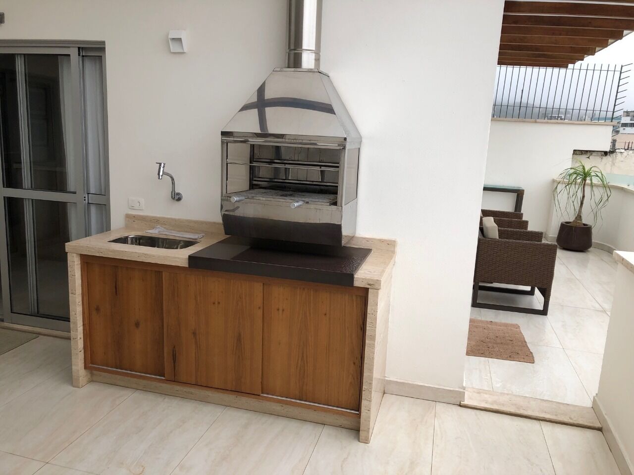 Een keuken met een inbouwoven, een spoelbak en een houten kast.