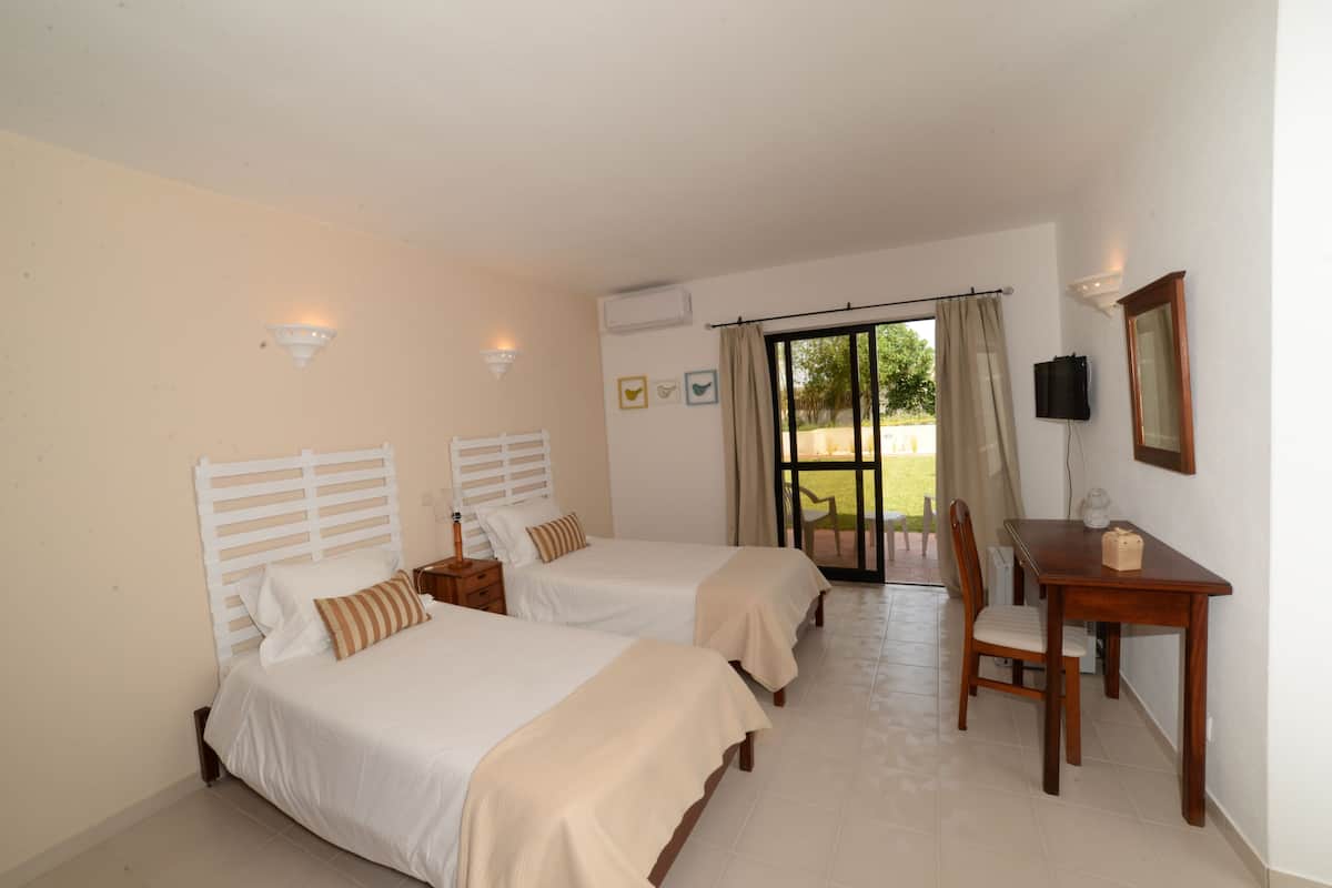 A hotel room with two beds, a desk, a chair, and a television.