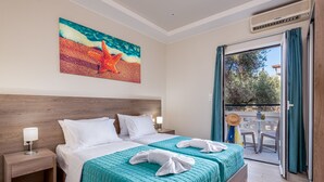 A hotel room with a large bed, two bedside tables, a painting of a beach scene, and a balcony with a table and chairs. - Sisi Breeze Hotel (Agios Nikolaos)