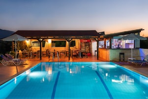 Una piscina con sillones de descanso y una zona de bar.