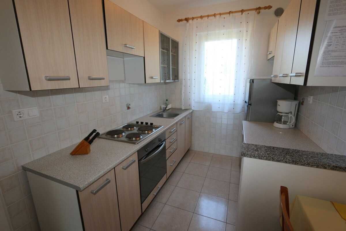 A kitchen with light wooden cabinets, a gas stove, a dishwasher, and a coffee maker.