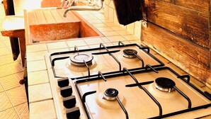 A gas stove with four burners, a sink, and a wooden wall.