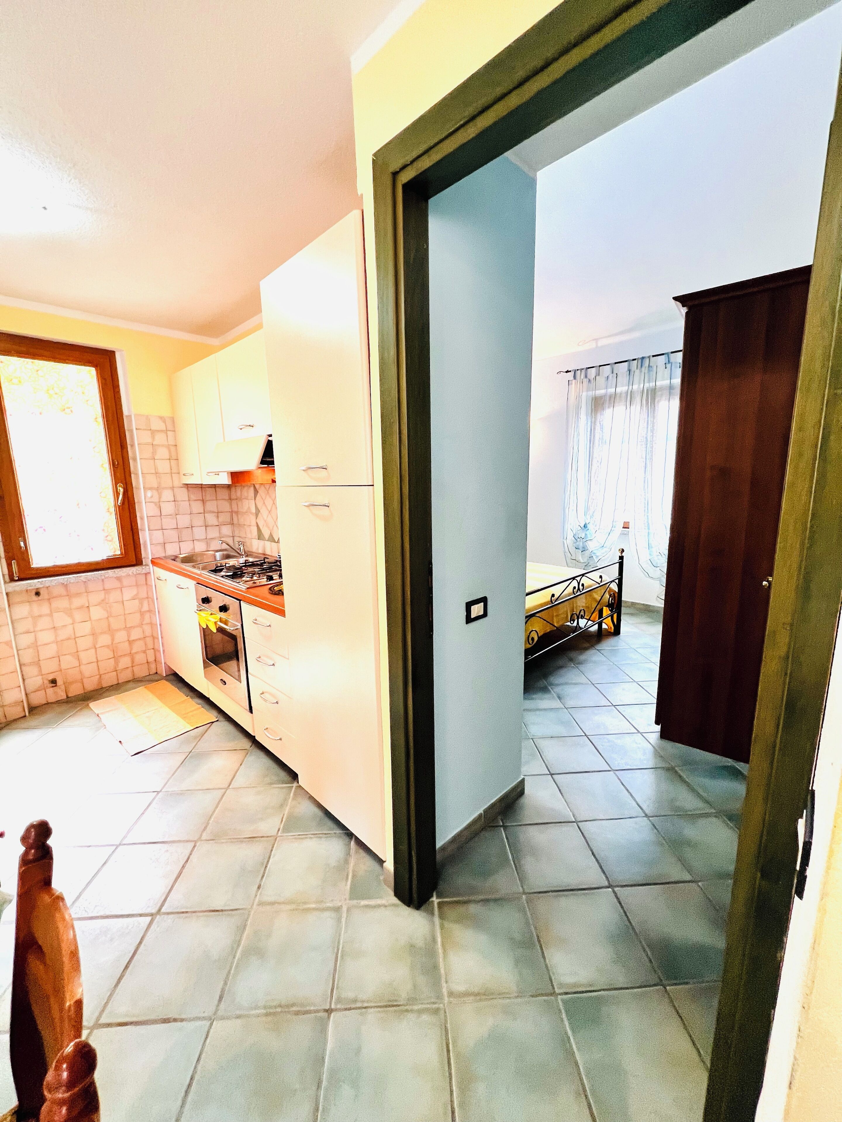 A kitchen with white cabinets, a stove, and a tiled floor.