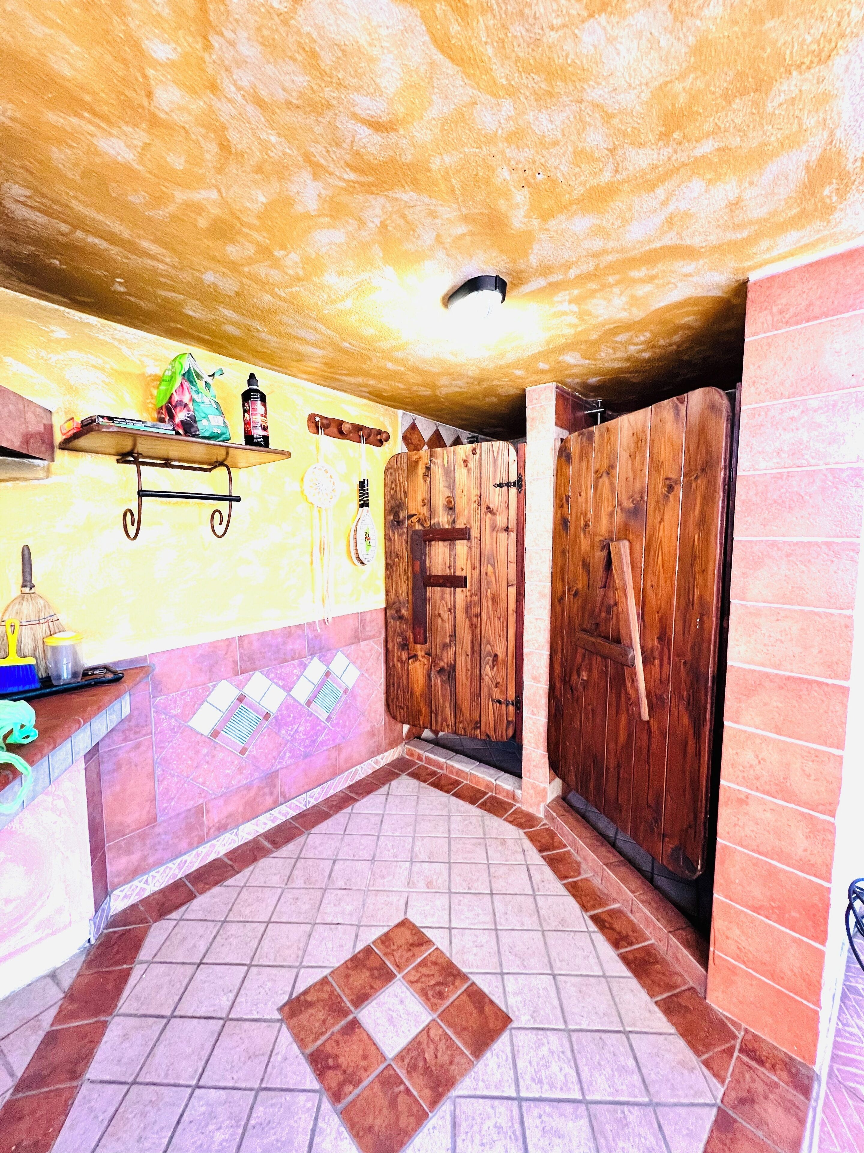 A bathroom with wooden doors, a shelf with toiletries, and a tiled floor.