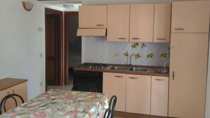A compact kitchen with light-colored cabinets, a stove, and a sink. - Appartamenti San Teodoro VII (San Teodoro)