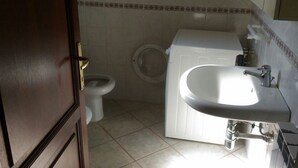 A bathroom with a toilet, a sink, and a washing machine. - Appartamenti San Teodoro VII (San Teodoro)