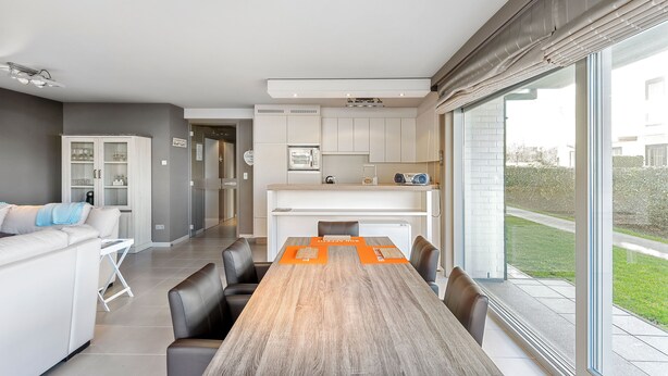 Un espacio habitable moderno con comedor, cocina y ventanas amplias que ofrecen vistas al exterior.