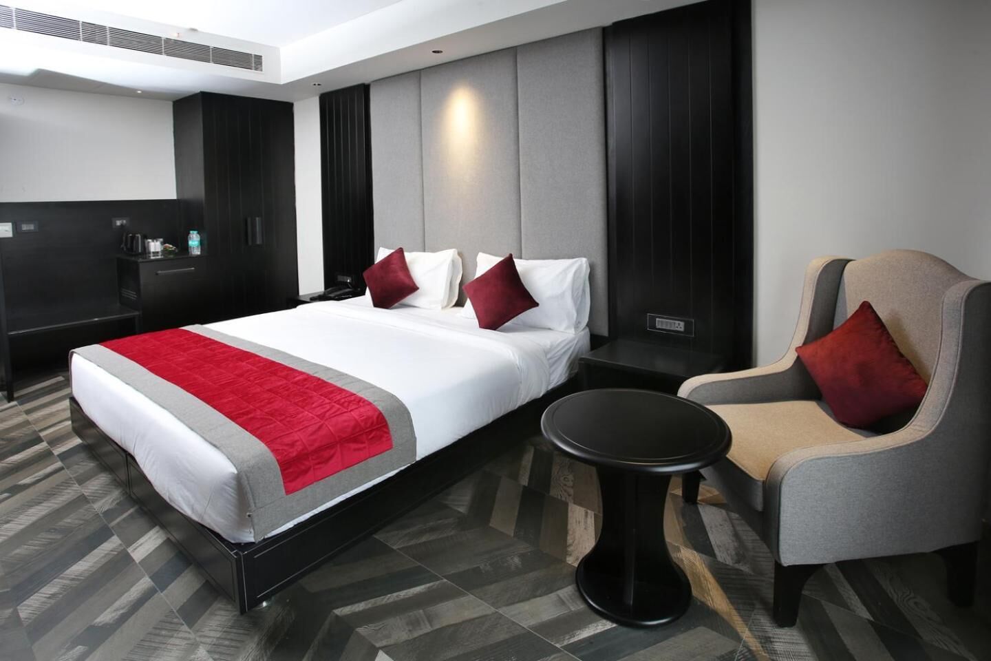 Een hotelkamer met een bed, een stoel, een tafeltje en een minibar.