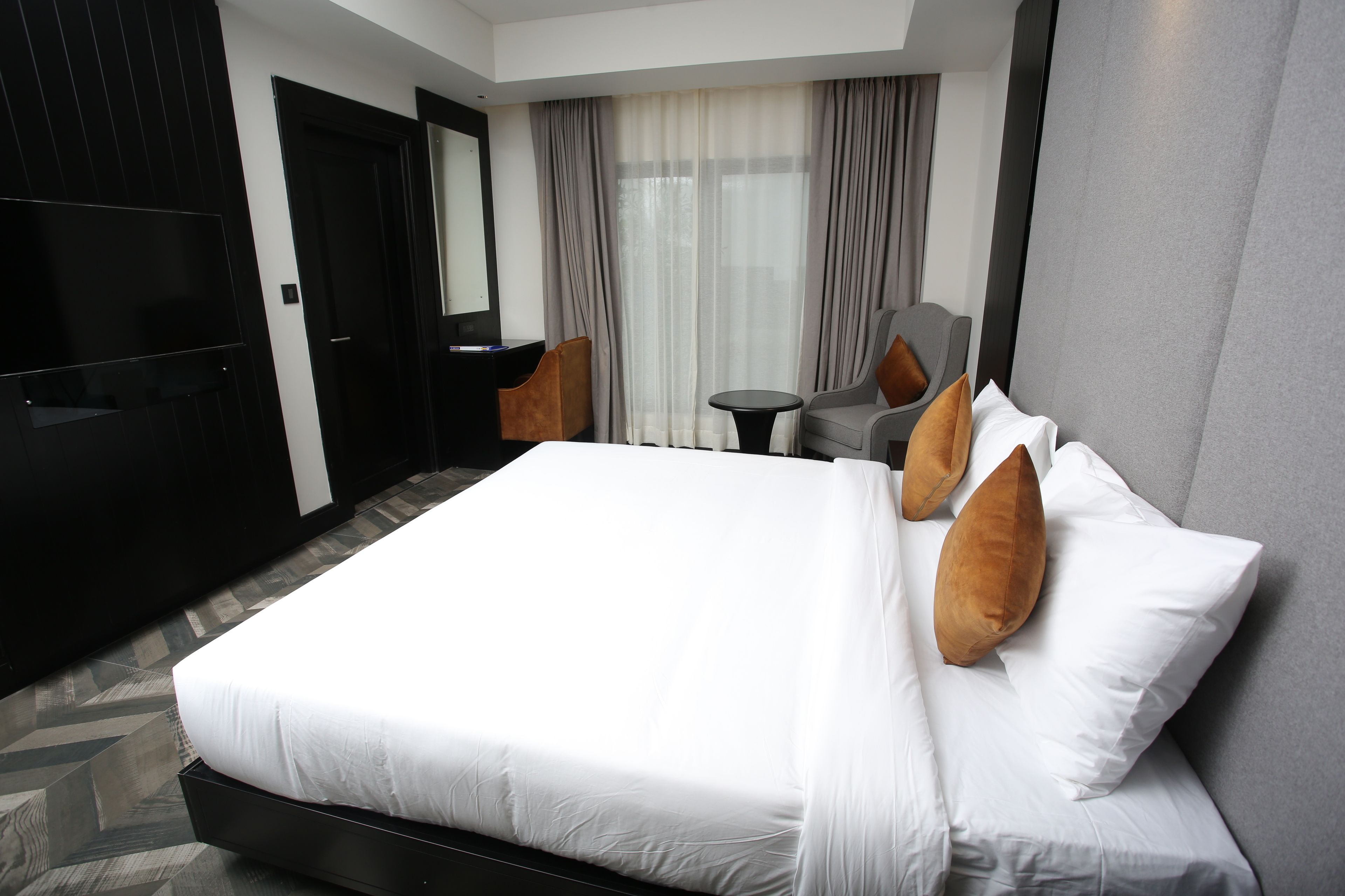 Una habitación de hotel con una cama grande, televisión, escritorio y silla.