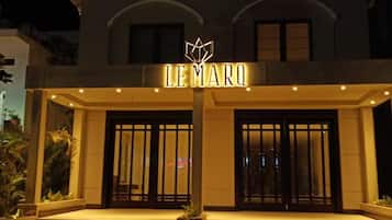 A hotel entrance with a sign reading 'LE MARQ' and a set of steps leading up to the doors.