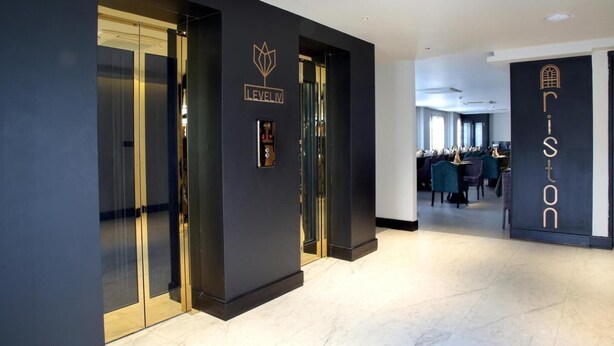 Una moderna hall d'albergo con porte in vetro, una reception e un'area salotto.