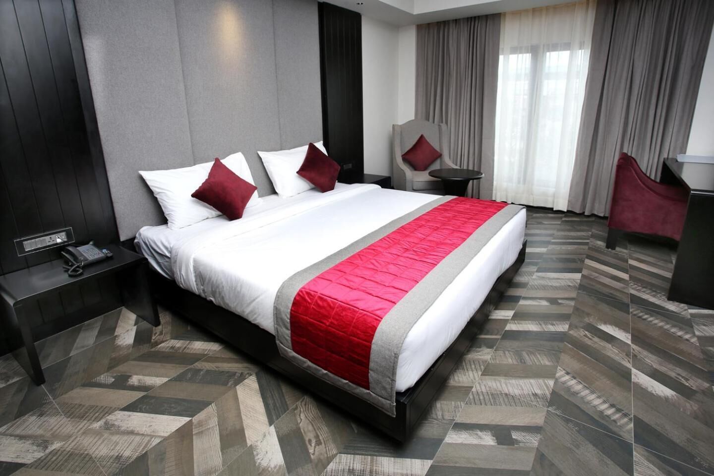 A modern hotel room with a large bed, a desk, and a chair.