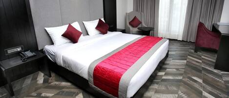 A modern hotel room with a large bed, a desk, and a chair.