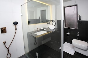 Et moderne badeværelse med en glasafskærmet brusekabine, en vask med et spejl over og et toilet.