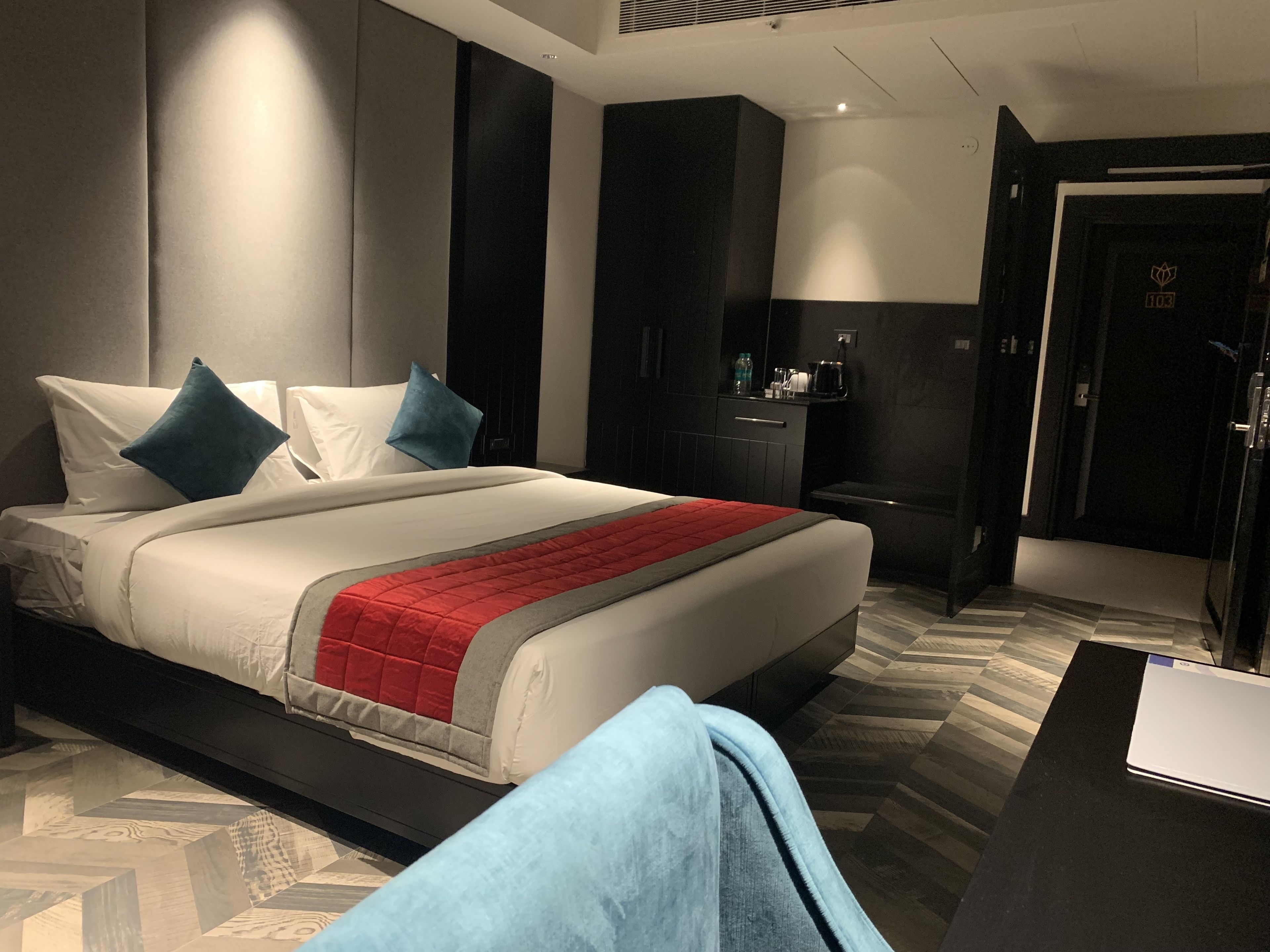 A modern hotel room with a large bed, a desk, and a wardrobe.