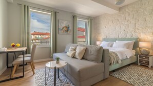 A modern hotel room with a bed, a sofa, a small table, and a desk. - Luxurious Suites Elegance (Zadar)