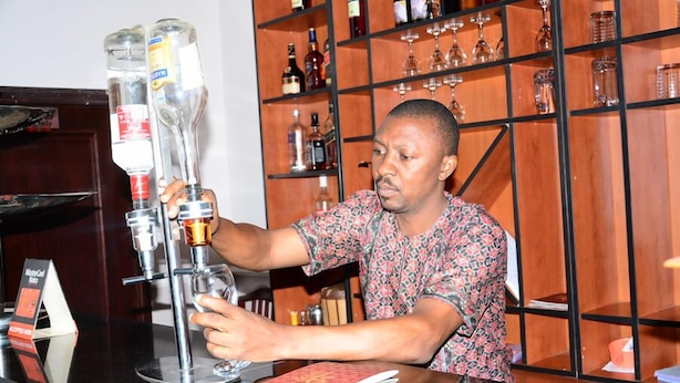 A person pouring a drink from a tap into a glass. - Marvel Hotel  Suites (Abuja)