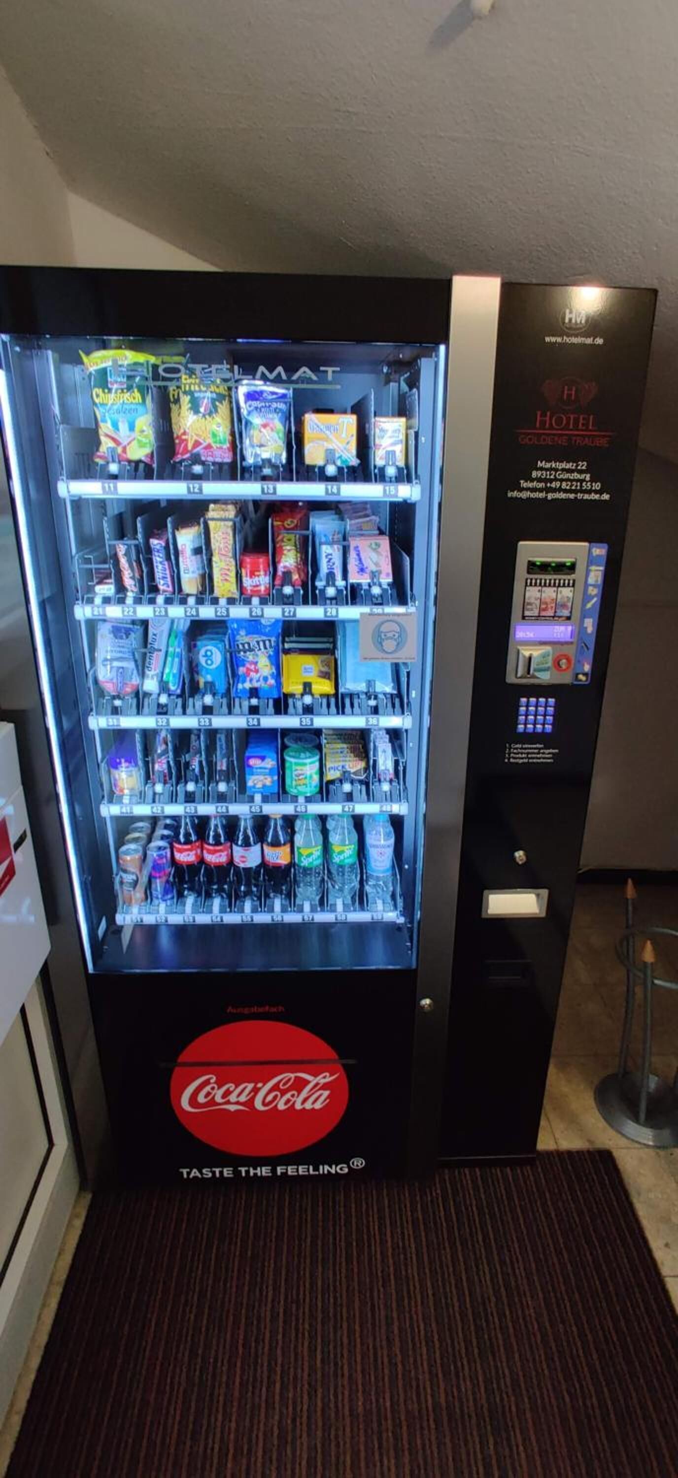 A vending machine stocked with snacks and drinks, including a Coca-Cola logo.