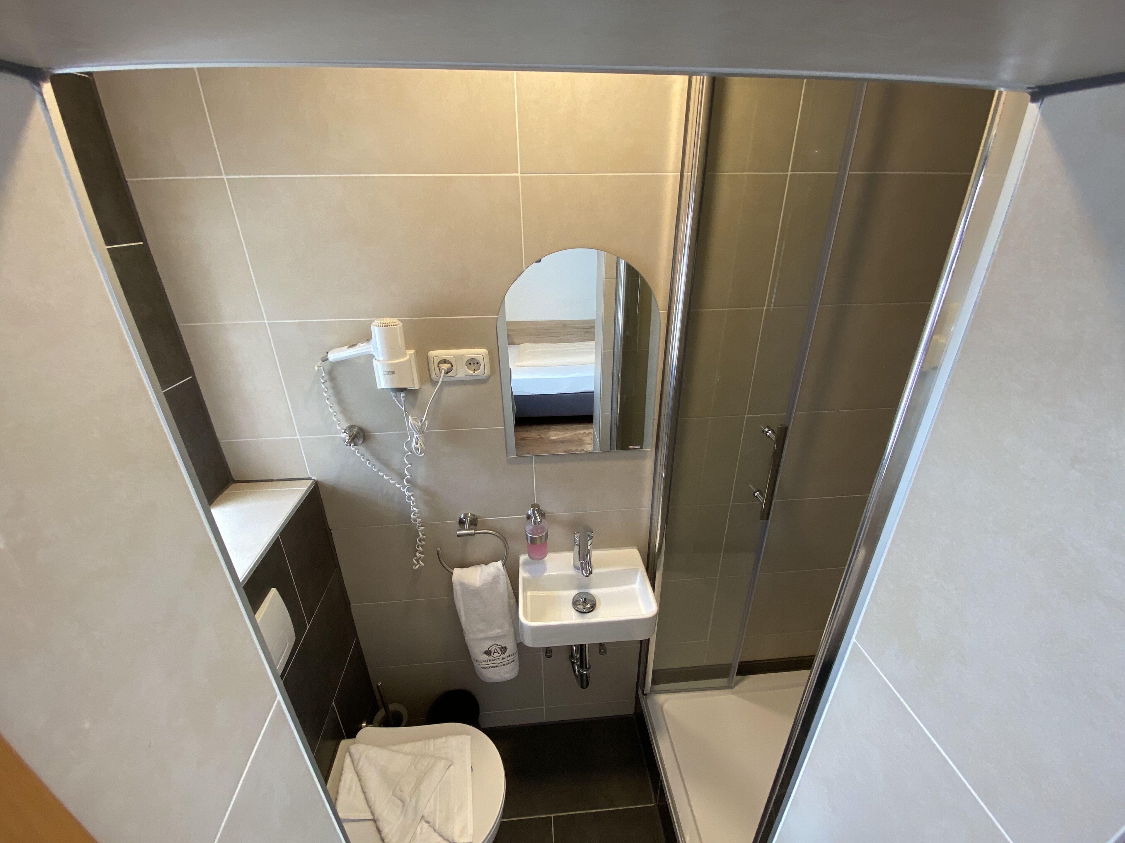 A compact bathroom with a shower, toilet, and sink.