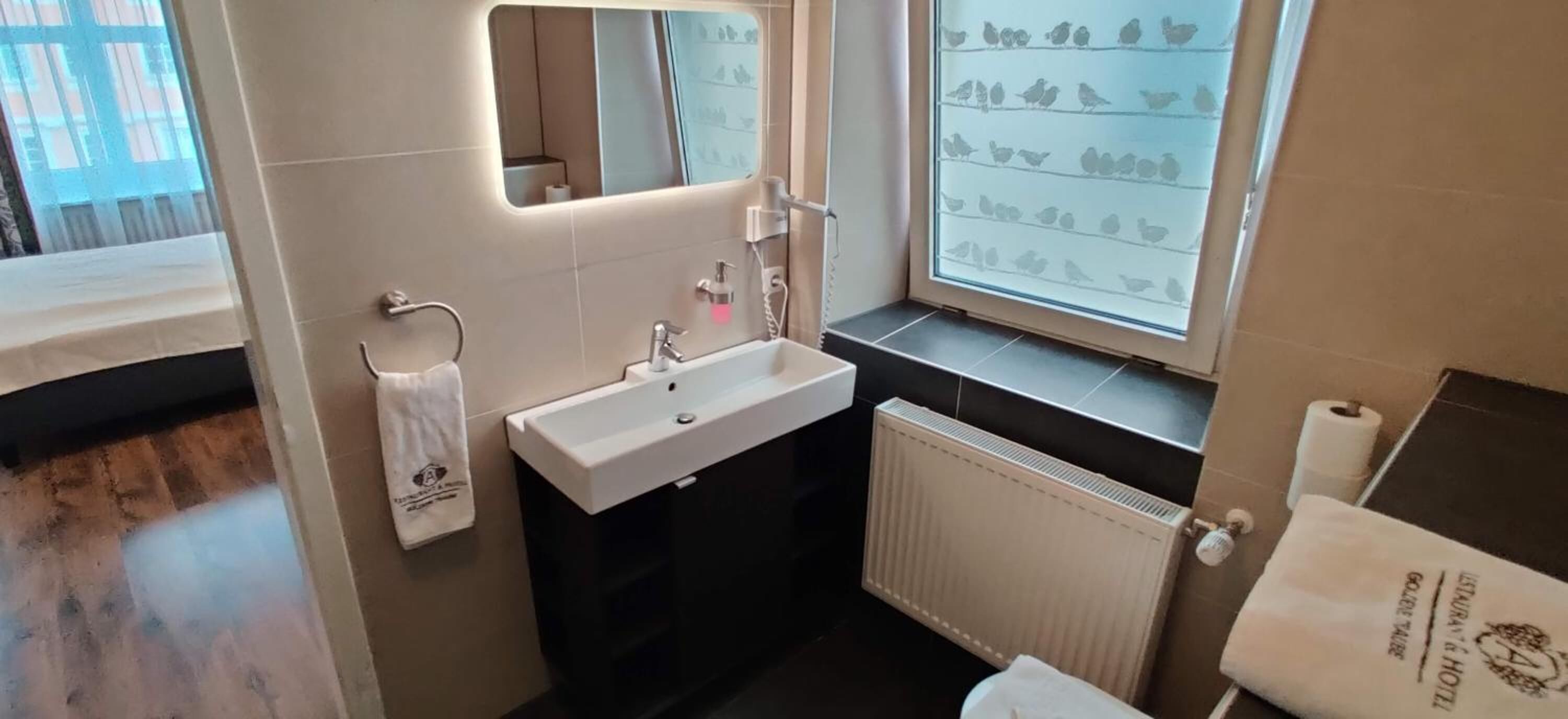 A bathroom with a white sink, mirror, and towel rack.