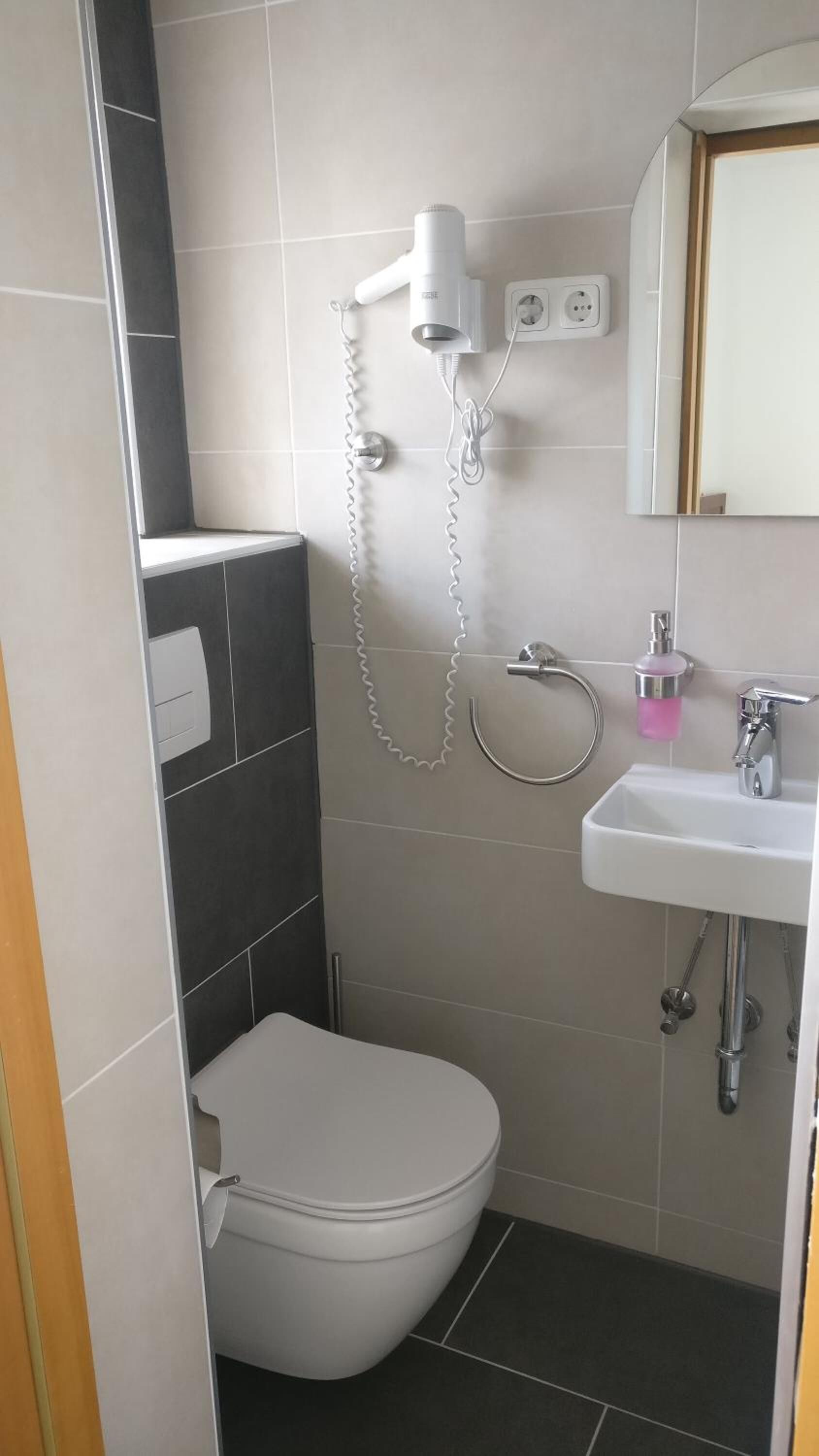Une salle de bain moderne équipée de toilettes, d’une douche et d’un lavabo.