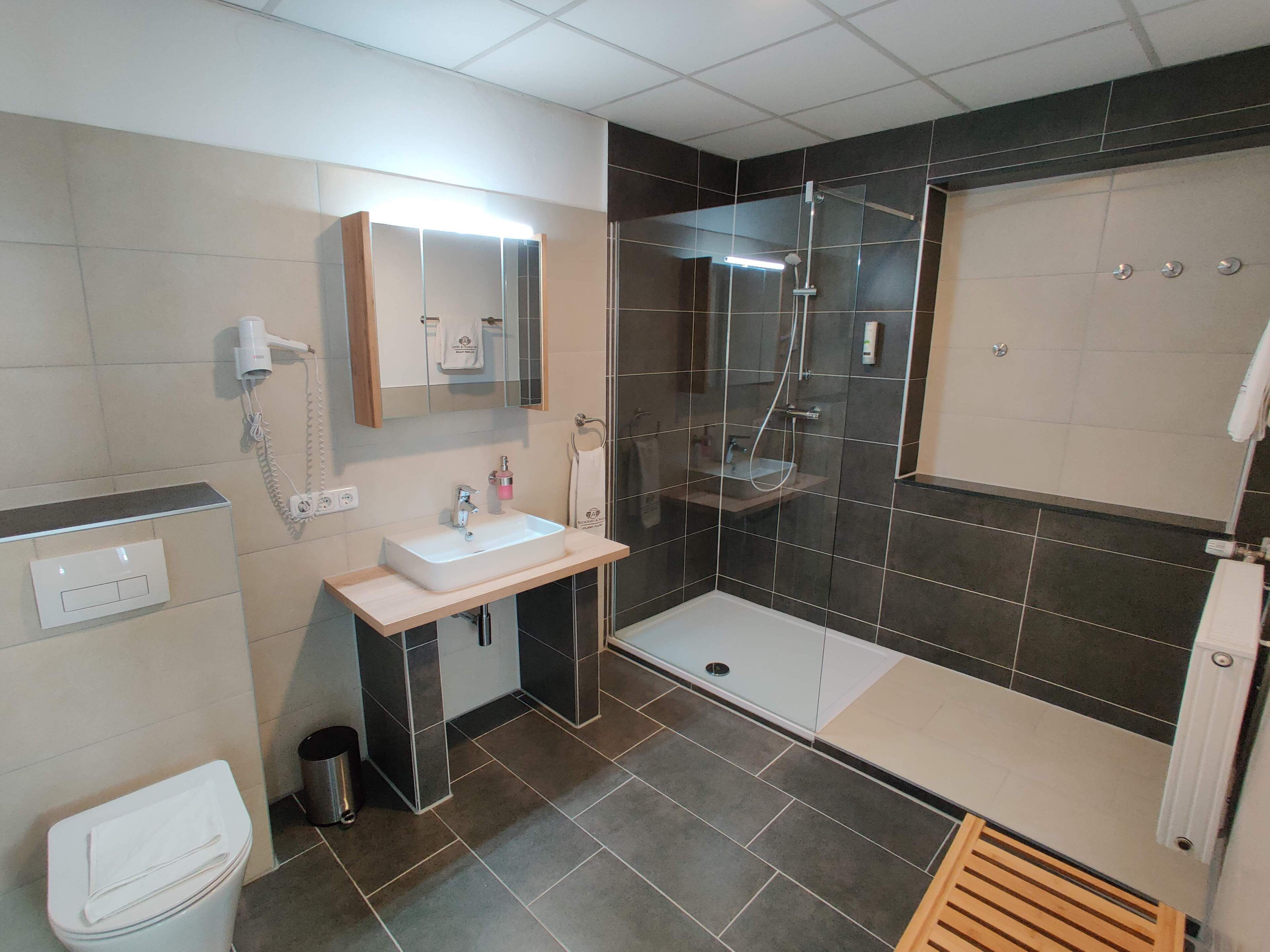 Ein modernes Badezimmer mit Waschbecken, Spiegel und Dusche.