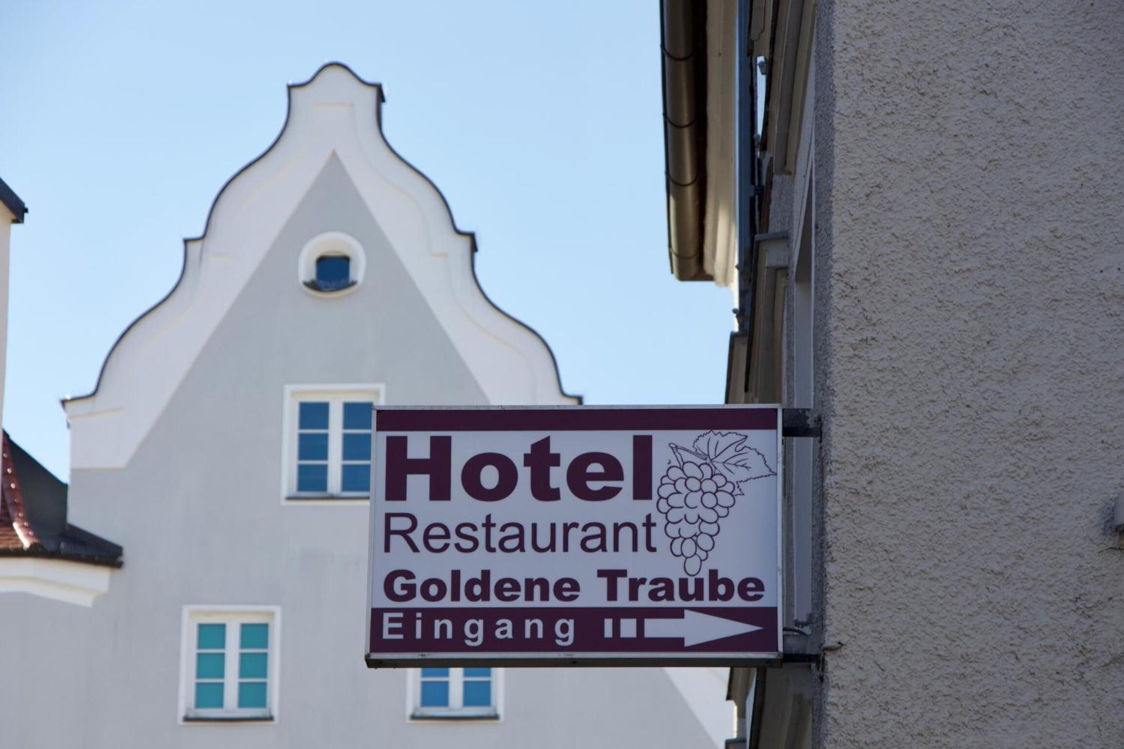 Une enseigne indiquant un hôtel et un restaurant appelés « Goldene Traube », avec une flèche pointant vers la droite.