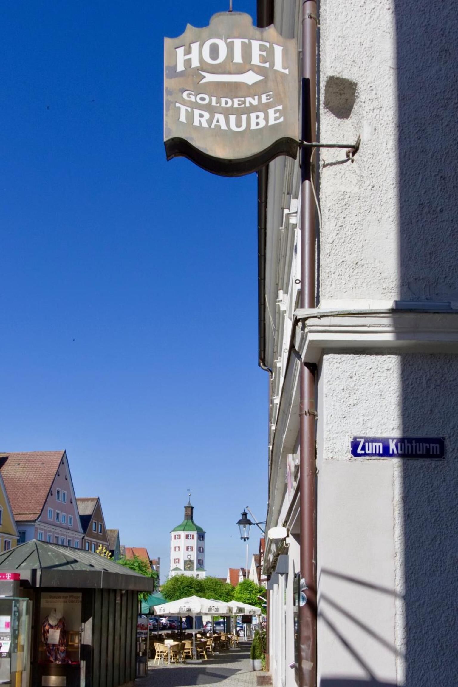 Un cartel de hotel con la leyenda "HOTEL GOLDENE TRAUBE" y una señal de calle que dice "Zum Kuhturm".