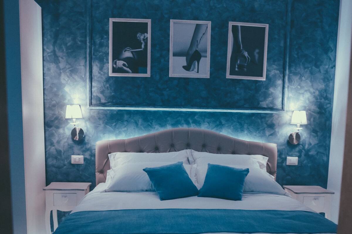 Una camera da letto con un letto grande, due comodini con lampade e tre quadri appesi al muro.