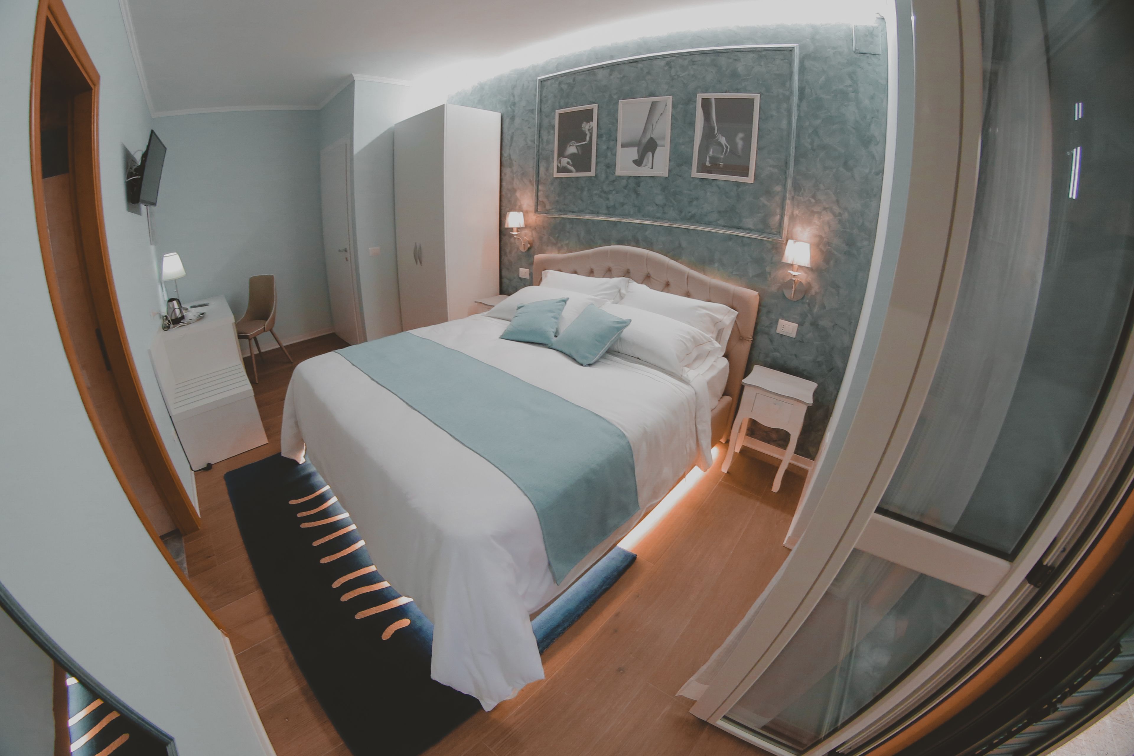 A modern bedroom with a large bed, bedside tables, a wardrobe, and a TV on the wall.